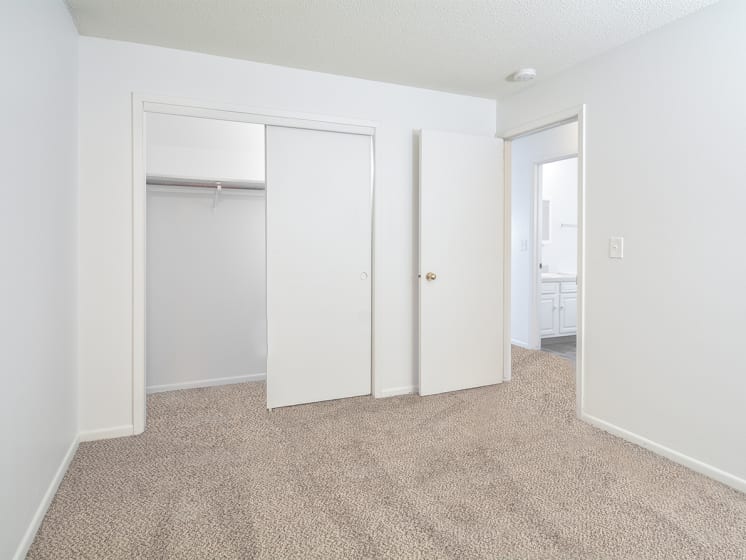 Carpeted Bedroom with Sliding Closet Doors and White Walls