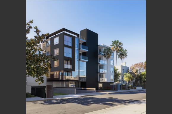 a tall building with a street in front of it and palm trees