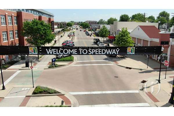 A street view of a town with a sign that reads "Welcome to Speedway".