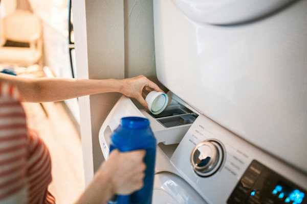 A person is pouring detergent into a washing machine at Twenty Fair Apartments, New Haven, Connecticut
