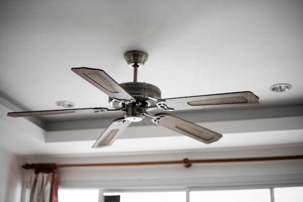 A ceiling fan with five blades is mounted on a white ceiling.