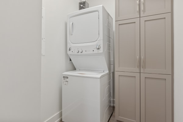 a washer and dryer in a laundry room with white cabinets