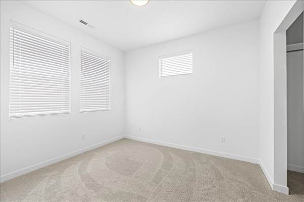 A room with a carpeted floor and a window with blinds.