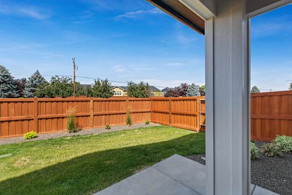 A view from a house looking out to a wooden fence and green lawn. at AVIA Lofts on Victors Way, Boise Idaho