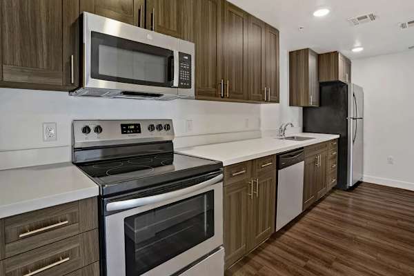 A modern kitchen with brown wooden cabinets and stainless steel appliances. at 605 Place Student Housing & Co-Living, Utah, 84770
