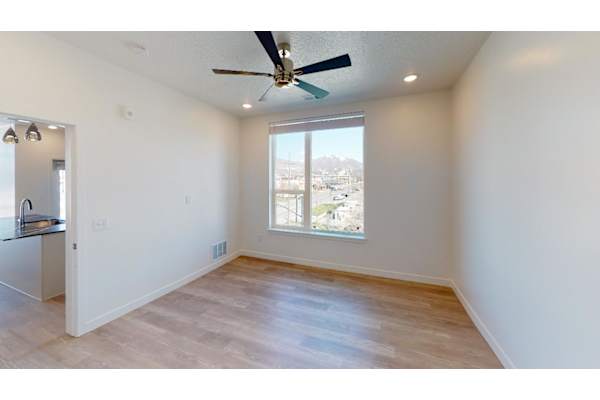 A room with a ceiling fan and a window overlooking a cityscape.