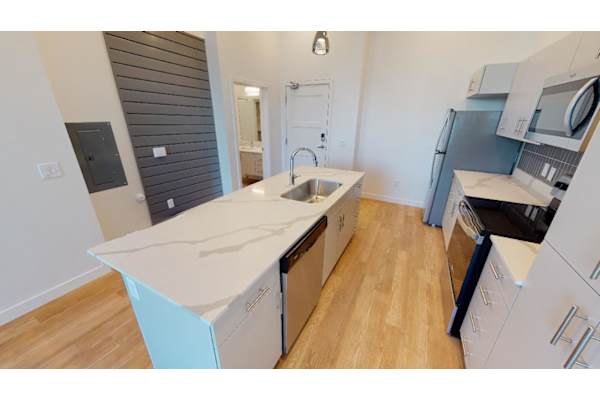 A kitchen with a white counter top and wooden floors.