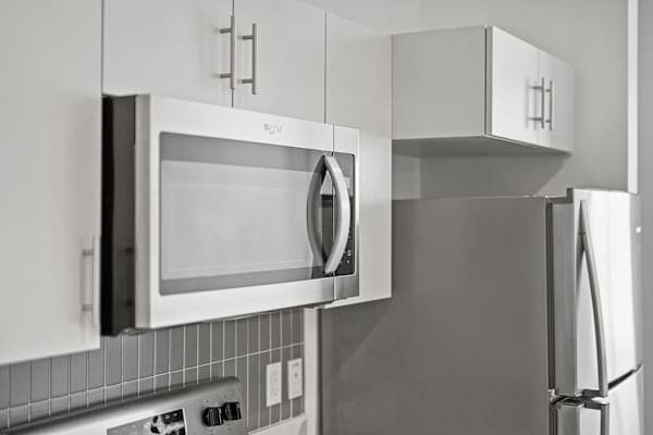 A black and white photo of a kitchen with a microwave and refrigerator.