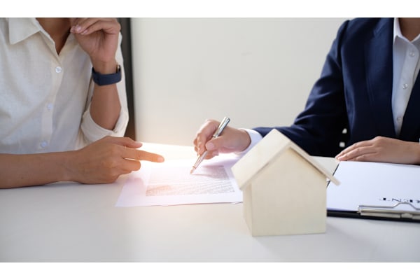 A person in a white shirt is signing a document with a pen while another person in a blue suit is pointing at the document. at 605 Place Student Housing & Co-Living, St George