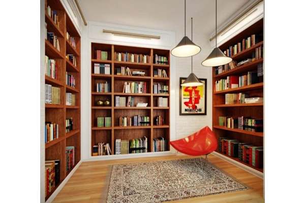 a library with wooden shelves and a red chair
