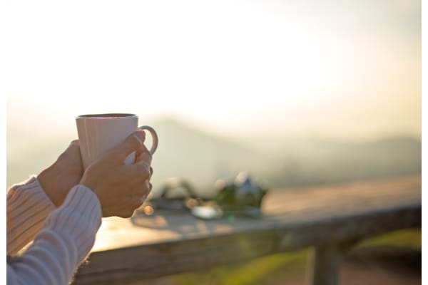 a person holding a cup of coffee on a balcony
