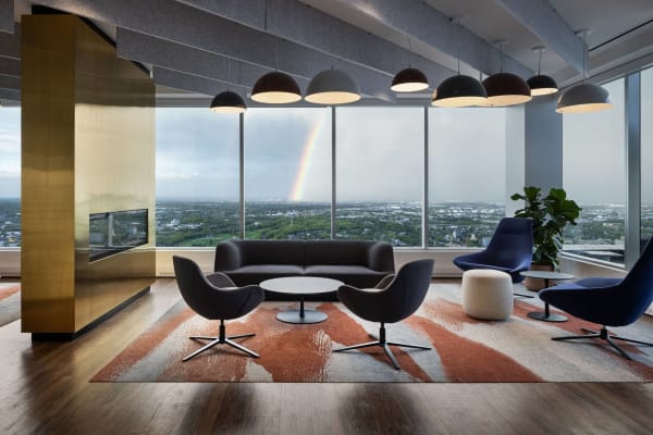 a lounge area with chairs and a table and a rainbow in the window