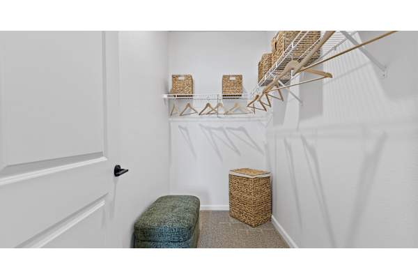 A white hallway with a bench and a basket on the floor.
