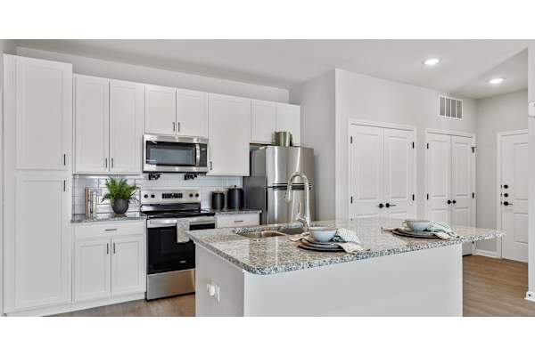 A modern kitchen with white cabinets and stainless steel appliances.