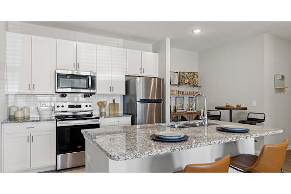 A modern kitchen with a granite countertop and stainless steel appliances.