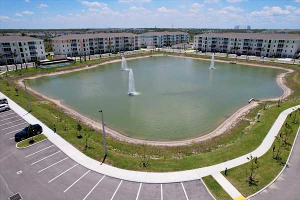 A round pond with a fountain in the middle of a parking lot.
