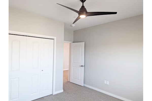 A room with a ceiling fan and two doors.