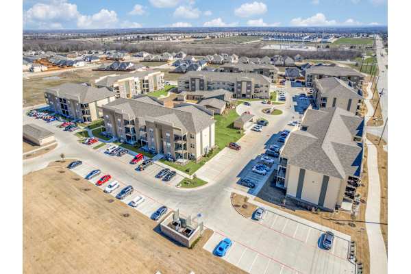 A large apartment complex with a parking lot in front.