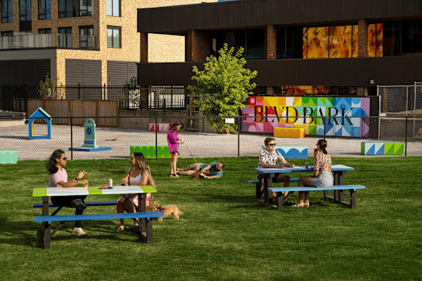 A group of people are sitting at picnic tables in a park.