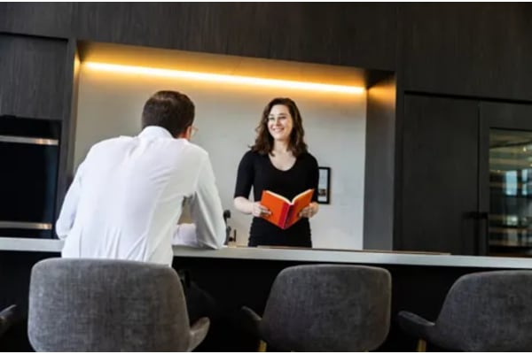 A woman is reading a book to a man in a white shirt.