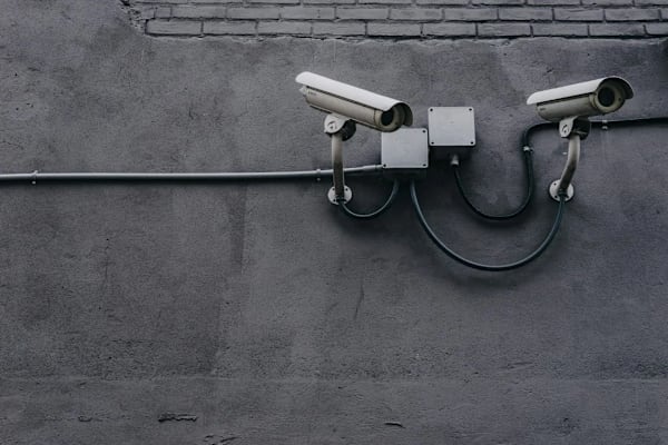Two CCTV cameras are mounted on a grey wall.