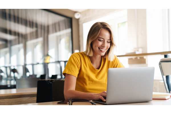 A woman in a yellow shirt is using a laptop at The Maverick Apartments, Kitchener, N2H 0E3