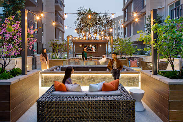 a couple sitting on a couch in front of a pool in an apartment complex