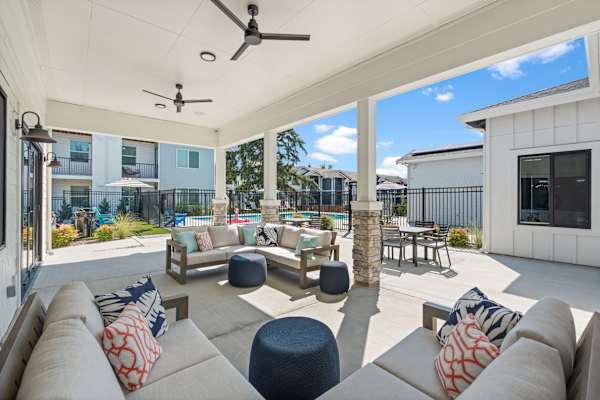 A patio with a white ceiling and a fan, furnished with a couch and a table.