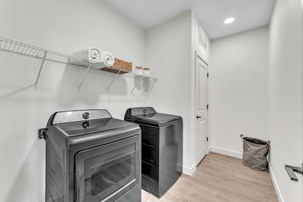 The Plaza at Pinnacle Hills laundry room with full-size washer and dryer and white shelving