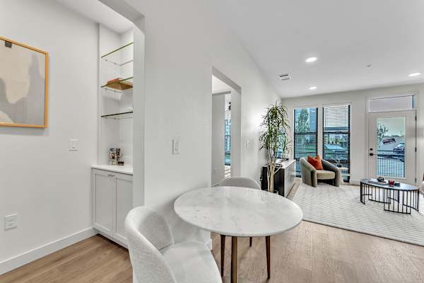 The Plaza at Pinnacle Hills built in shelves, round table with chair and living room with large windows and door leading to balcony