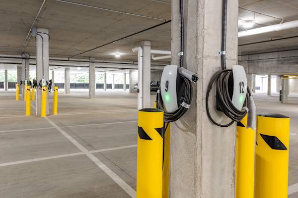 A parking garage with yellow poles and charging stations.