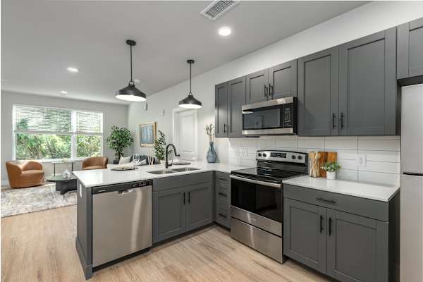 A modern kitchen with dark grey cabinets and stainless steel appliances.