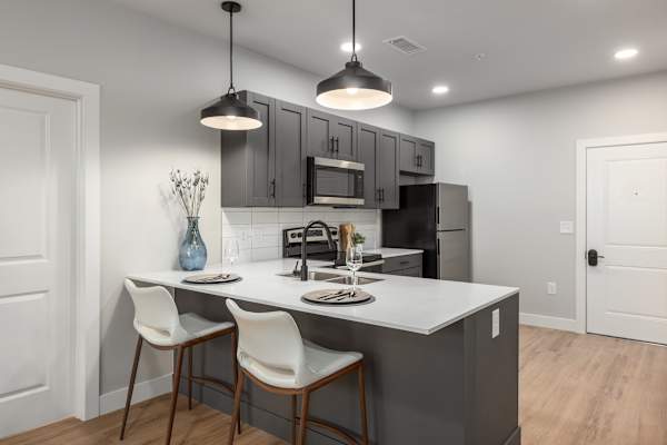 A kitchen with a white countertop and grey cabinets.