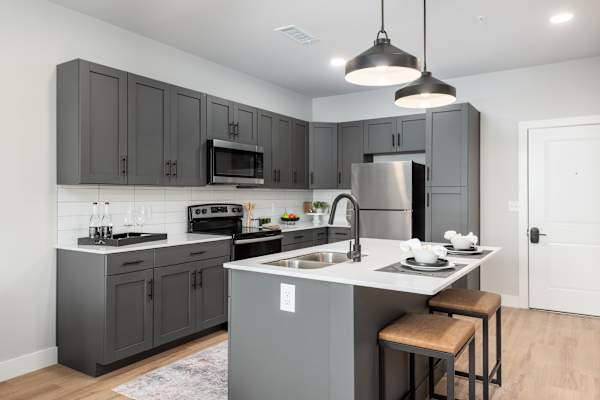 A modern kitchen with a white countertop and grey cabinets.