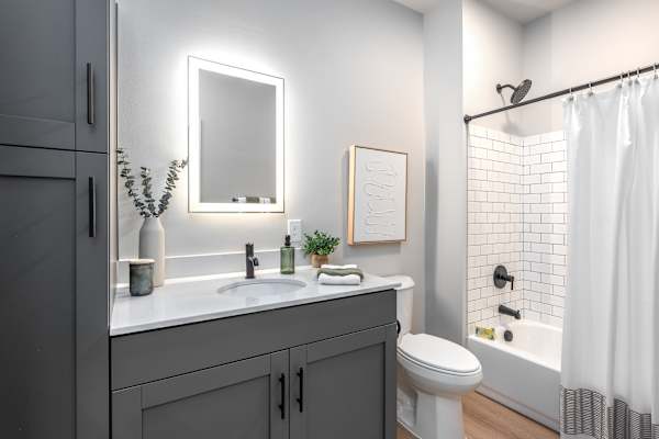 A modern bathroom with a white sink and grey cabinets.
