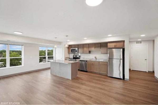 A modern kitchen with wooden floors and stainless steel appliances.