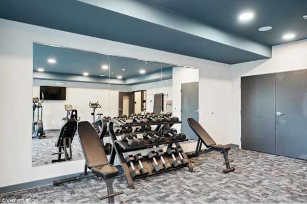 A gym with a mirror, weights, and exercise equipment.