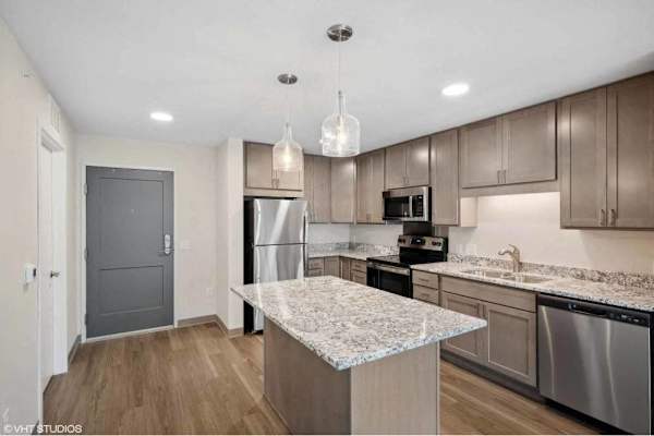 A kitchen with a granite countertop and stainless steel appliances.