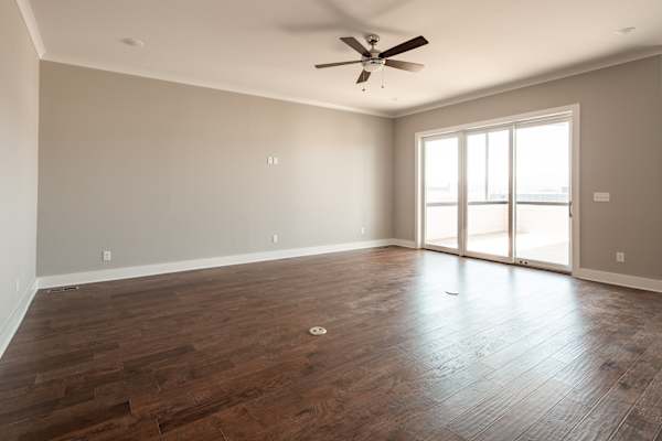 A room with a ceiling fan and sliding glass doors.