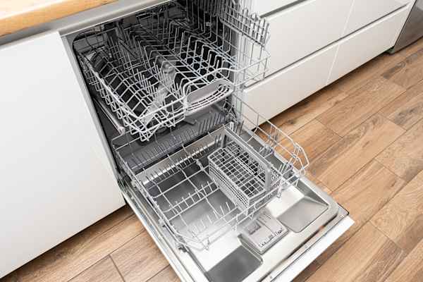 A dishwasher with its door open and racks inside.
