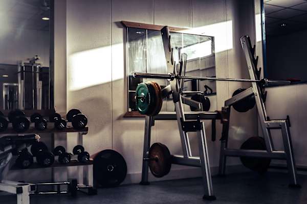 A gym with a weight bench, dumbbells, and a barbell.
