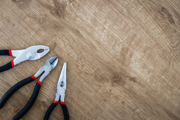three pairs of scissors and a pair of pliers on a wooden table