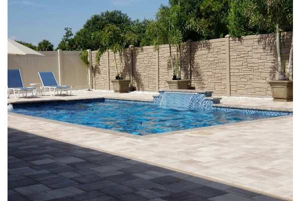 A pool with a waterfall and a stone wall.