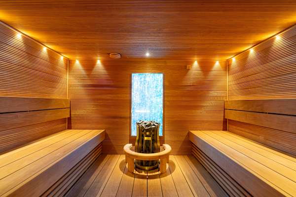 A wooden sauna with a window and lights on the wall.