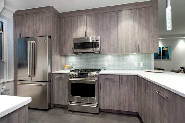 A modern kitchen with a stainless steel refrigerator and oven.