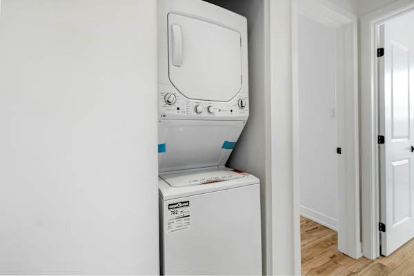 A white dryer is installed in a wall next to a white door.
