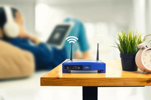 a wireless router on a table with a person sitting on a couch in the background