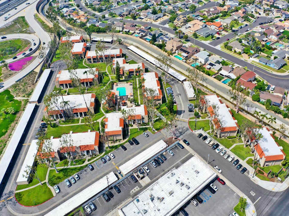 A bird's eye view of a residential area with houses and a parking lot.
