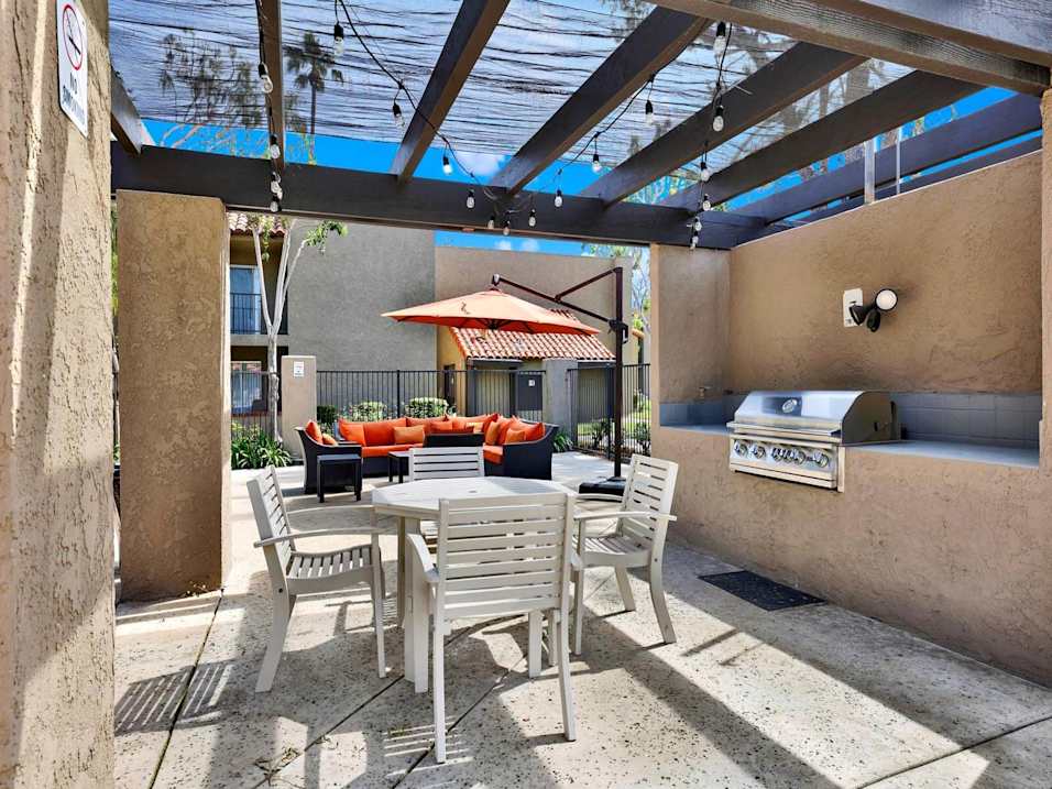 A patio with a table and chairs under a roof.