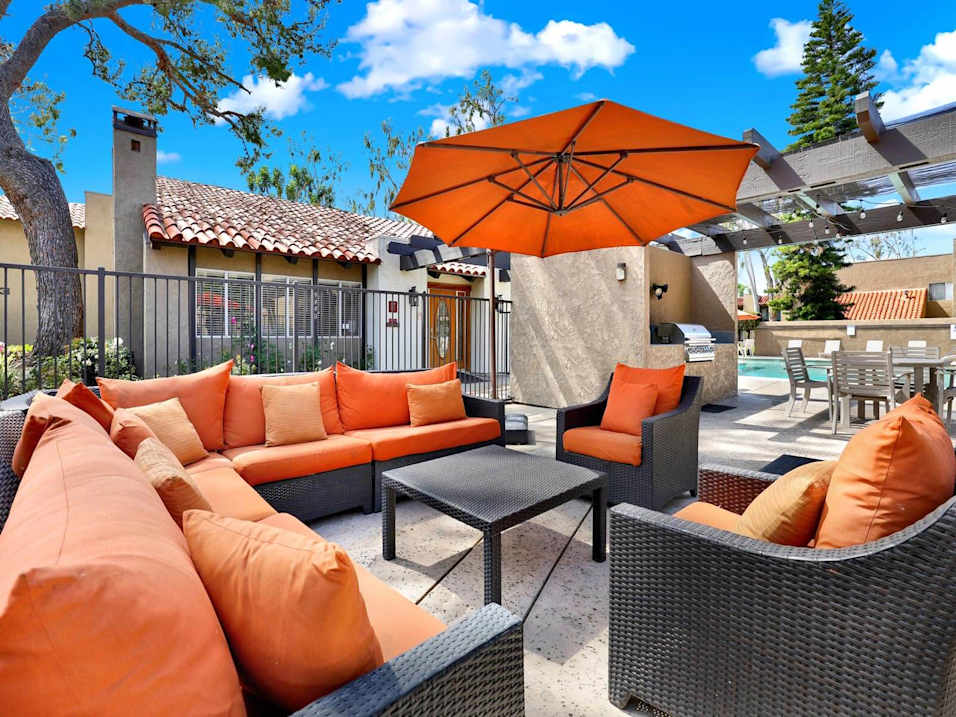 A patio with orange cushions and a black table.